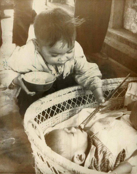 Bé Nam dùng đũa bón thức ăn cho em gái mình tại một trung tâm cứu trợ quốc tế dành cho trẻ em ở Quy Nhơn.