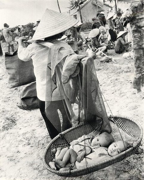 Hai trẻ sinh đôi nằm trên quang gánh cùa một bà mẹ đang di tản khỏi vùng chiến sự ở phía Nam Quảng Trị, 3/7/1972.