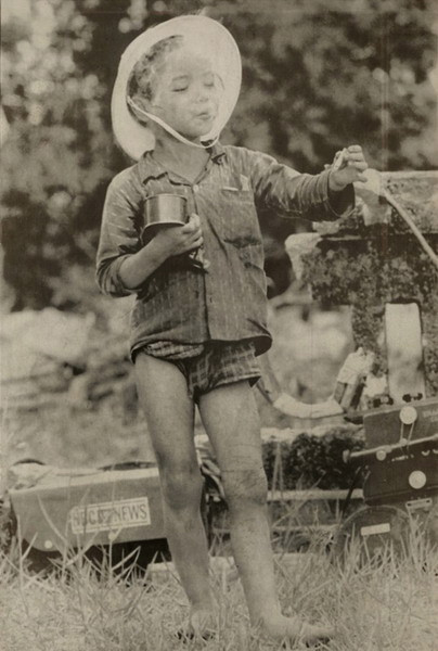 Một em bé tản cư tỏ ra rất mãn nguyện với một tay cầm hộp thực phẩm, tay kia cầm điếu thuốc do lính Mỹ đưa cho và miệng nhả khói thuần thục, ngày 1/5/1967.