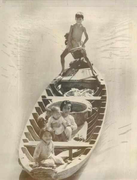 Một cậu bé lái thuyền máy chở gạo từ ngôi làng của mình đến chợ Vĩnh Long, ngày 19/12/1969. Trên thuyền còn có 3 đứa em của cậu.