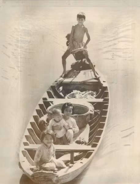 Một cậu bé lái thuyền máy chở gạo từ ngôi làng của mình đến chợ Vĩnh Long, ngày 19/12/1969. Trên thuyền còn có 3 đứa em của cậu.