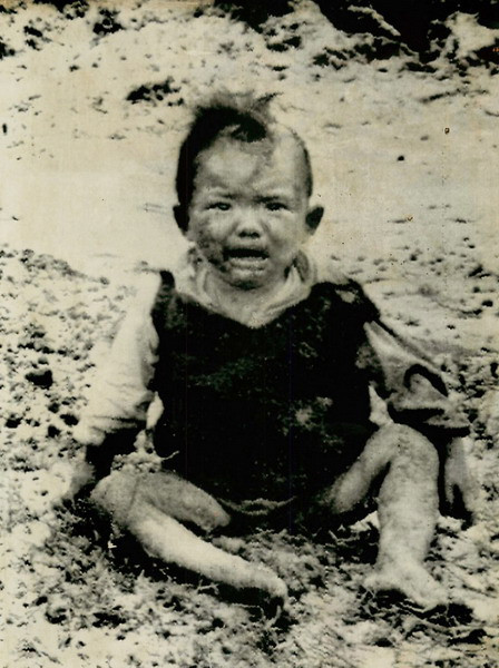 Em bé ngồi khóc trên mặt đường ở Nam Quảng Trị sau khi chiếc xe chở em cùng đoàn người di tản bị trúng mìn và nổ tung, ngày 27/4/1972. 40 người đã chết và hàng chục người khác bị thương trong vụ việc này.