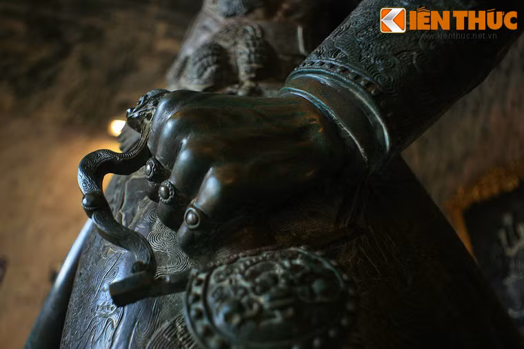 Tay trái của Vua Khải Định nắm chuôi gươm. Ba ngón tay đều đeo nhẫn mặt hoa nổi cao.