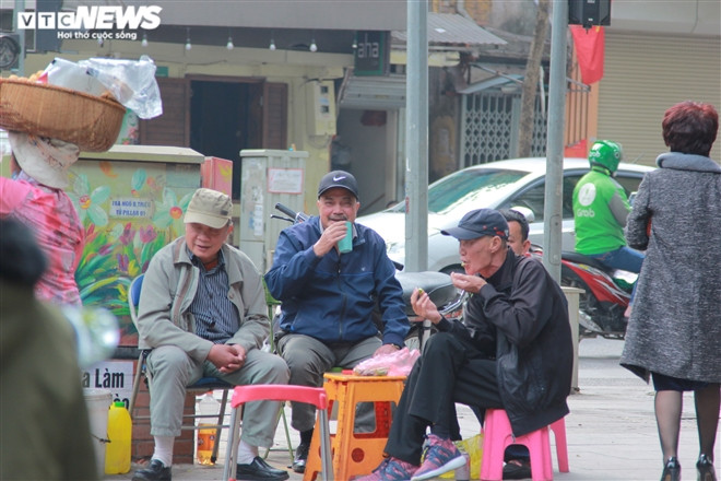 Trên phố Bà Triệu, một nhóm đàn ông mang đồ ăn, nước uống ra ngoài đường ngồi hàn huyên, họ vô tư cười nói như không hề có dịch bệnh COVID-19.