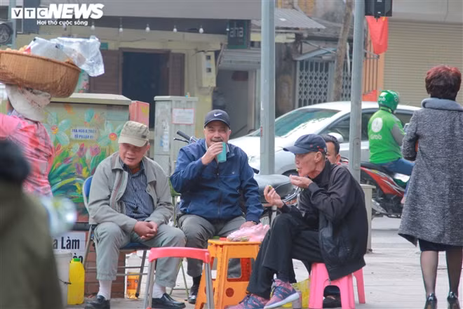 Trên phố Bà Triệu, một nhóm đàn ông mang đồ ăn, nước uống ra ngoài đường ngồi hàn huyên, họ vô tư cười nói như không hề có dịch bệnh COVID-19.