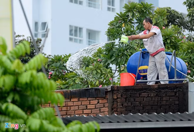 Trên mái nhà bên cạnh, nhân viên cửa hàng xe máy dùng nước dội vào hiện trường.