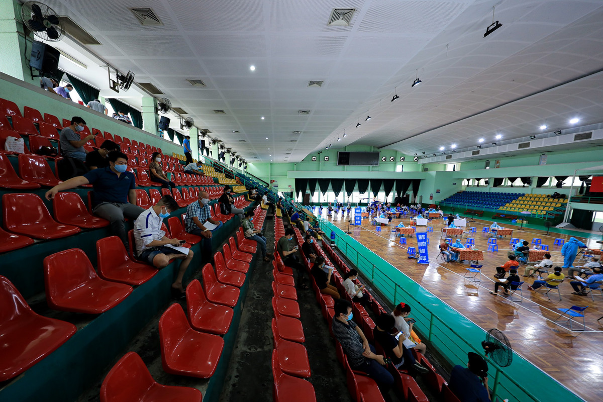 Bên trong nhà thi đấu, ban tổ chức tăng cường tuyên truyền bằng việc bố trí nhiều loa phát thanh liên tục nhắc nhở người dân giãn cách, trật tự, chờ tới lượt.
