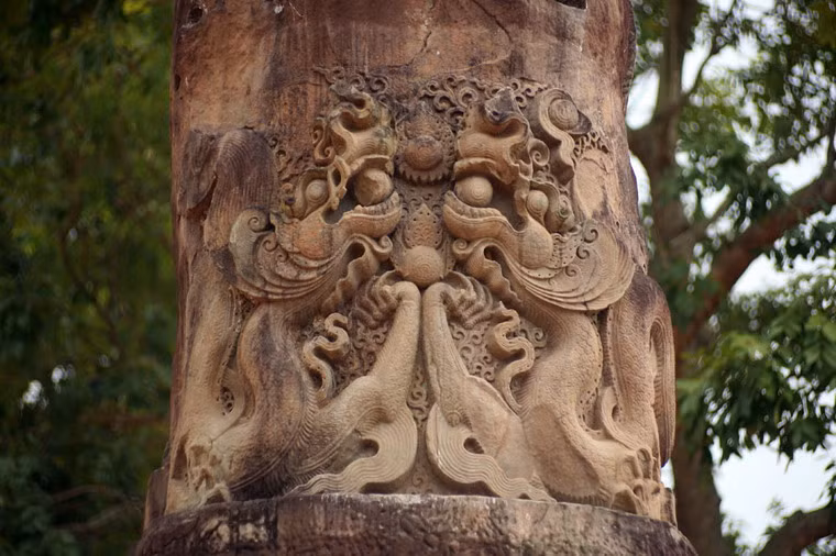 Đoạn dưới khối trụ tròn chạm nổi đôi rồng phong cách thời Lý với mào bốc lửa, bờm thành búi như cờ đuôi nheo bay lướt, thân tròn lẳn uốn khúc thoăn thoắt, chân chim năm móng.