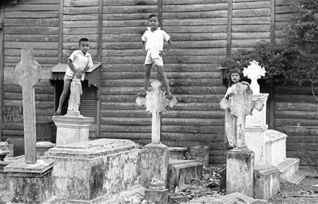 Những đứa trẻ đứng trên các ngôi mộ ở khu Mả Lạng, nơi chúng sống cùng gia đình. Bức tường phía sau chúng là của một cửa hàng mặt tiền hướng ra con đường chính.