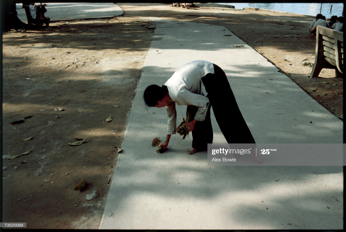 Người phụ nữ trung niên thu gom lá khô ở bờ hồ Hoàn Kiếm để bán cho những người mua về làm nhiên liệu đun bếp, 23/5/1983.