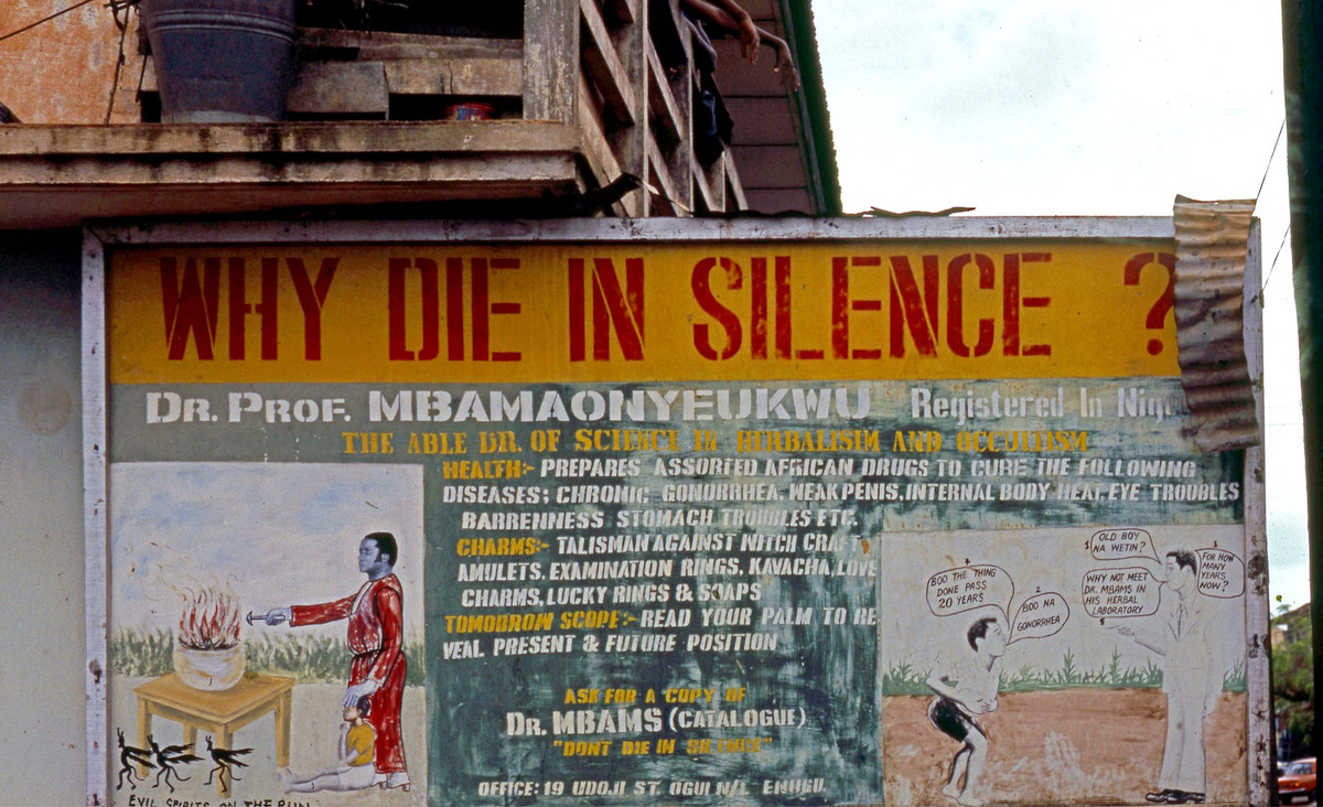 Pa-nô quảng cáo ở Enugu, có nội dung "Nếu bạn không muốn chết trong im lặng" với cảnh Giáo sư - Tiến sĩ Mbam xua đuổi tà ma và điều trị bệnh lậu.