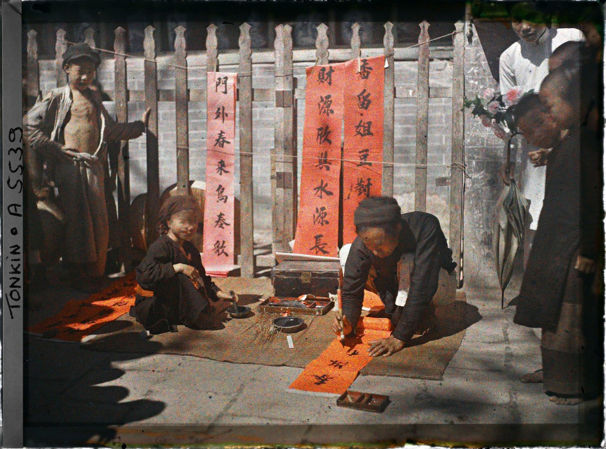 Ông đồ trẻ ngồi viết câu đối để bán cho khách qua đường mua về trang trí ngày Tết.