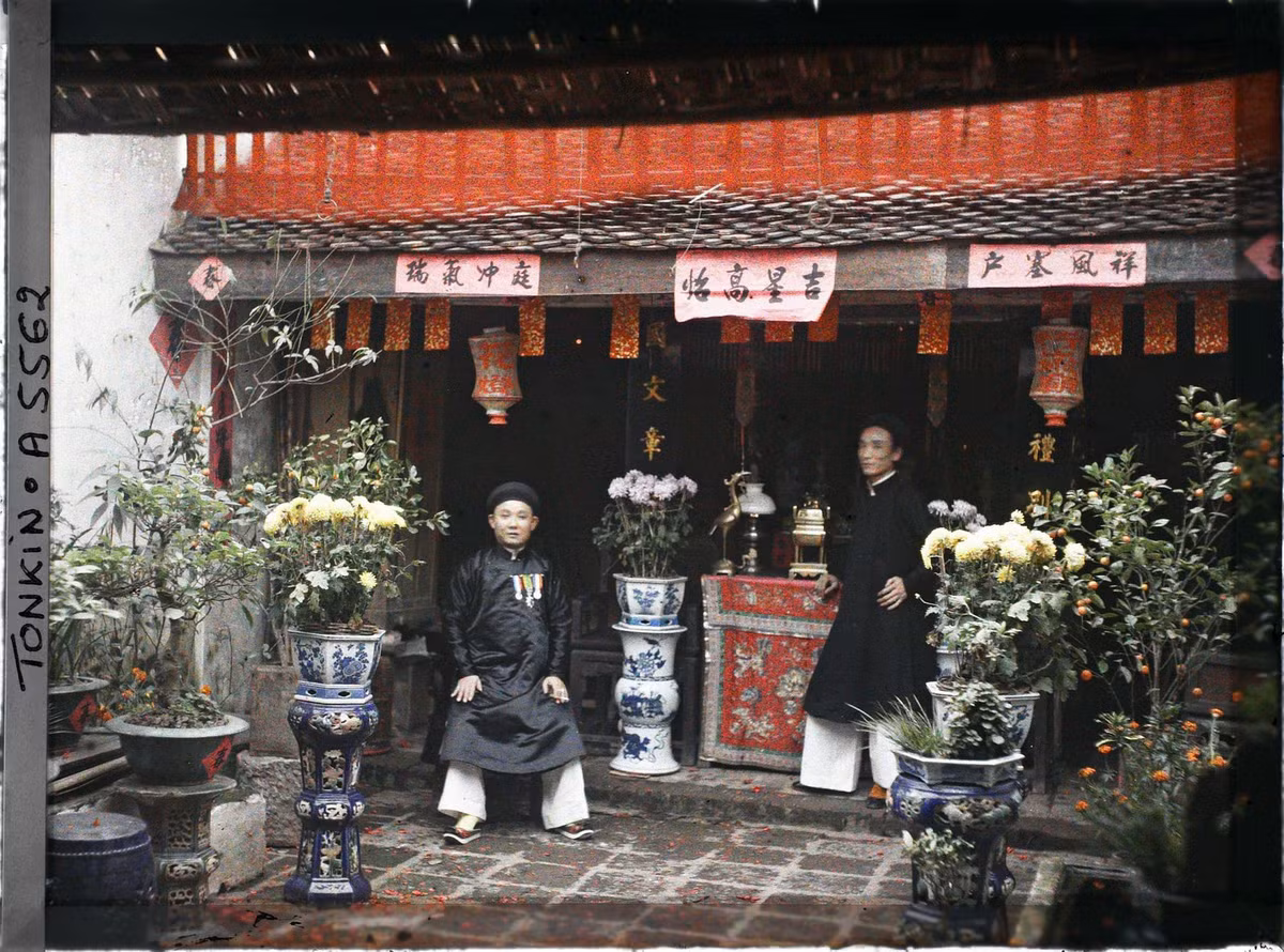 Hai hương chức trước bàn thờ tổ tiên trong sân của một ngôi nhà bế thế ở Hà Nội vào dịp Tết 1915.