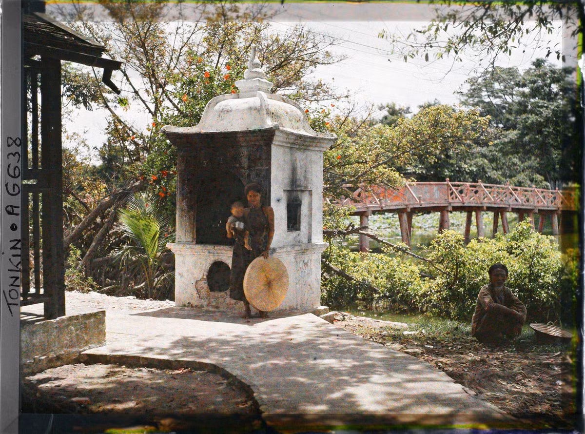 Hai mẹ con đứng bên lò hóa vàng mã ở gần cầu Thê Húc.