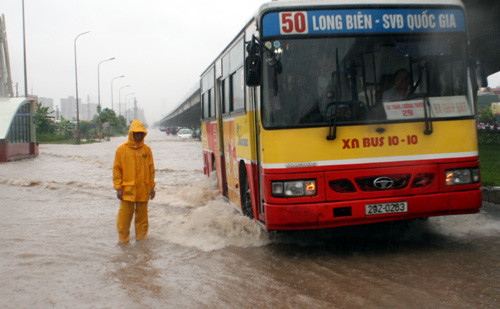 Công nhân cấp thoát nước đội mưa, làm "hoa tiêu" cho các chủ phương tiện lưu thông tránh vùng ngập sâu trên phố Nguyễn Xiển, quận Thanh Xuân.