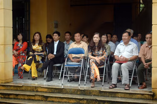 Các thầy cô giáo trường tiểu học Xuân Phương dự khai giảng ở hiên trường tránh mưa.