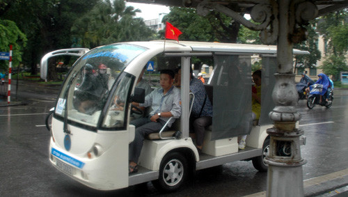 Xe điện du lịch cũng không bỏ lỡ cơ hội cắm cờ, chở khách chạy trên các tuyến phố cổ của Hà Nội trong tiết trời mưa nhẹ.