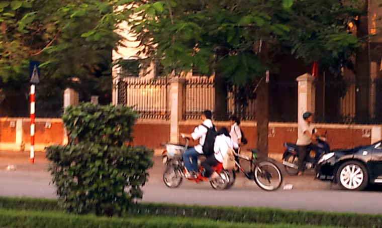 Nam sinh đi xe đạp điện không đội MBH chở bạn gái còn kéo theo xe đạp của bạn băng băng trên đường.