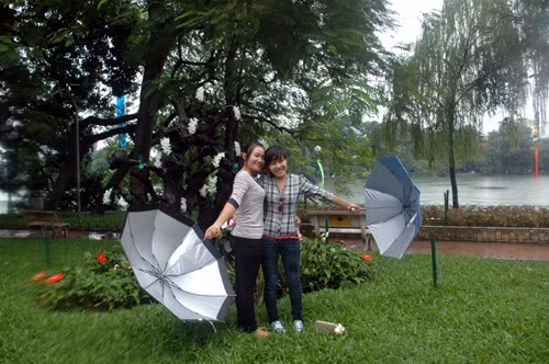 Các thiếu nữ bỏ ô che mưa chụp ảnh bên hồ Hoàn Kiếm, Hà Nội.