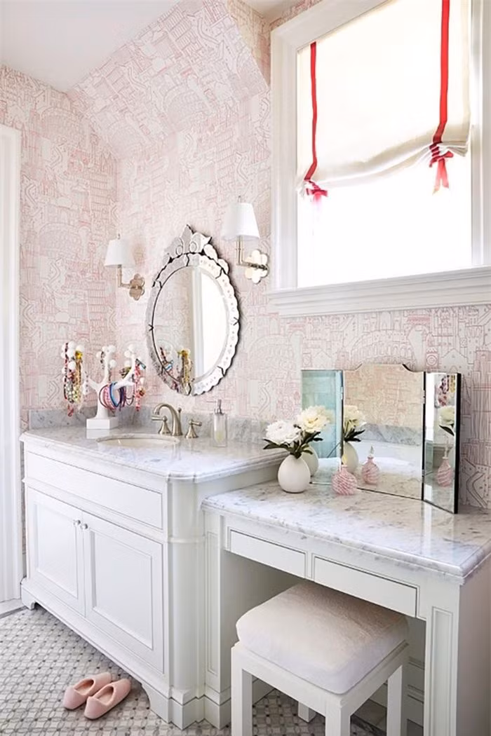 Bàn trang điểm và bồn rửa được lát đá cẩm thạch, phù hợp cùng với giấy dán tường màu hồng có hoa văn tinh tế. 