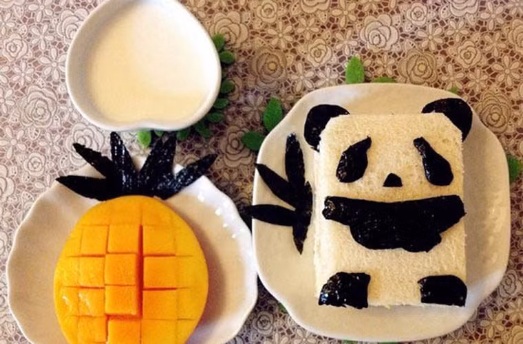 Một suất ăn đơn giản mô phỏng hình chú gấu trúc đáng yêu từ lát bánh mì và tấm rong biển đen dùng để cuộn sushi.