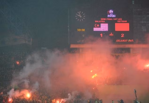 Các CĐV Malaysia đốt pháo sáng khi đội nhà thua 1-2 trước Việt Nam tại bán kết lượt đi AFF Cup 2014. Ảnh: Daily Mail.