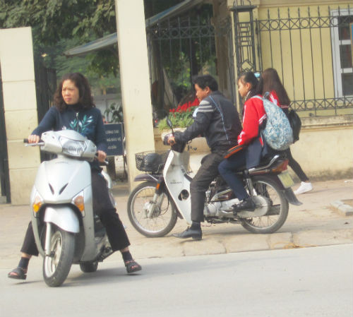 Không chỉ trẻ em không đội mũ bảo hiểm khi tham gia giao thông mà ngay cả các bậc phụ huynh cũng "quên" đội MBH khi đưa đón con. Hình ảnh được ghi tạiTrường THCS Dịch Vọng,86 Chùa Hà, Dịch Vọng, Cầu Giấy, Hà Nội