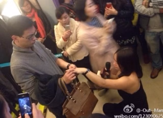 Người đàn ông được bạn gái mình cầu hôn tỏ ra chẳng mấy vui vẻ khi đeo chiếc nhẫn vào tay của cô gái mặc dù cô gái đã quỳ xuống và tự nguyện nâng tay của mình lên.