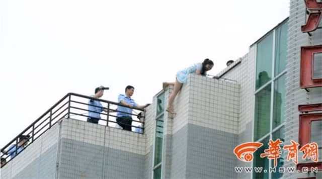 Cảnh sát đang cố gắng thuyết phục người phụ nữ xuống khỏi nơi nguy hiểm.