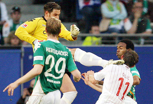 Tim Wiese (áo vàng) thua xa đàn anh Kahn về tài năng bóng đá và danh tiếng. Nhưng ở khoản hung hăng, dữ tợn, thủ môn người Đức của Bremen không hề kém cạnh. Ivica Olic, khi còn khoác áo Hamburg, hiểu rõ điều này khi lĩnh trọn vào mặt một cú đá như trời giáng của Wiese Tim.