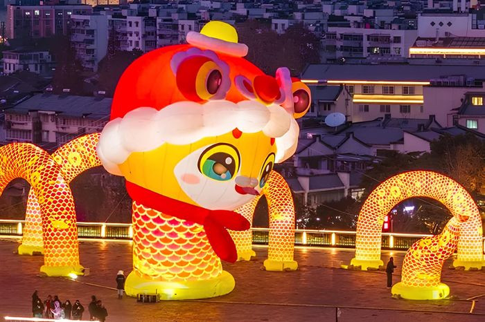 Linh vật rắn đầu đội nón lân, cổ quấn khăn quàng đỏ như đang bơi ra từ bức tường thành Nam Kinh (Giang Tô) cổ kính. Ảnh: Weibo