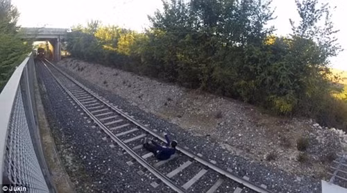 Cậu thiếu niên bắt đầu nằm xuống chờ đoàn tàu đi qua...