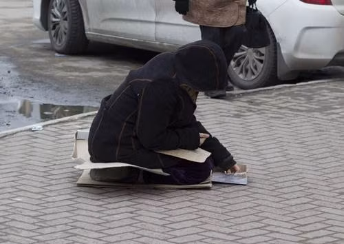 Người phụ nữ đang đếm những đồng xu mà cô được người đi đường bố thí.