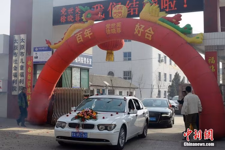 Đoàn xe rước dâu chạy qua cổng Trung tâm phúc lợi đã được trang trí hoành tráng.