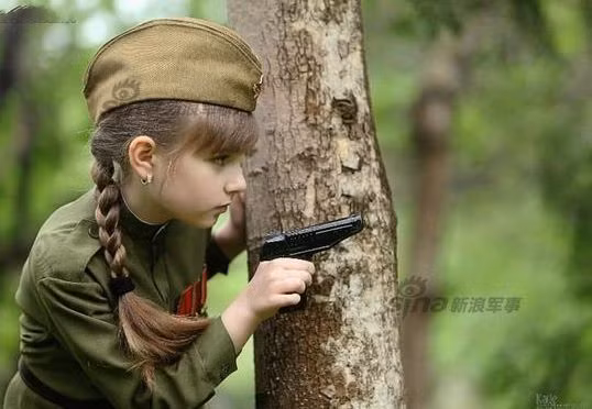 Bộ ảnh được thực hiện trong rừng với màu xanh làm nền chủ đạo nên càng làm nổi bật làn da trắng hồng của cô bé. Trong shot hình này, cô bé trông như một nữ chiến sĩ anh dũng của nước Nga.