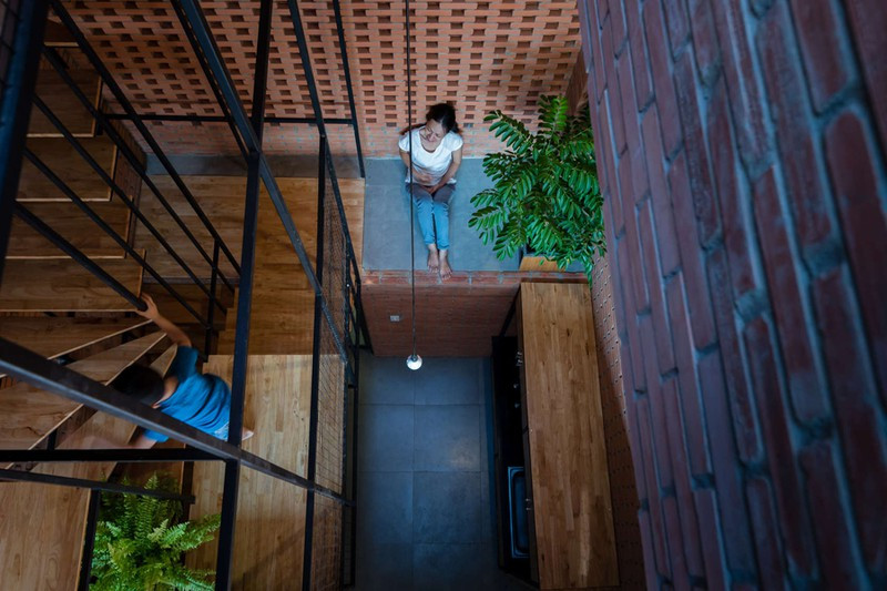 Bên cạnh cầu thang và phía trên phòng bếp là giếng trời để lấy sáng và thông gió. Hệ khung thép đóng vai trò vách ngăn nhưng không làm cản tầm nhìn.