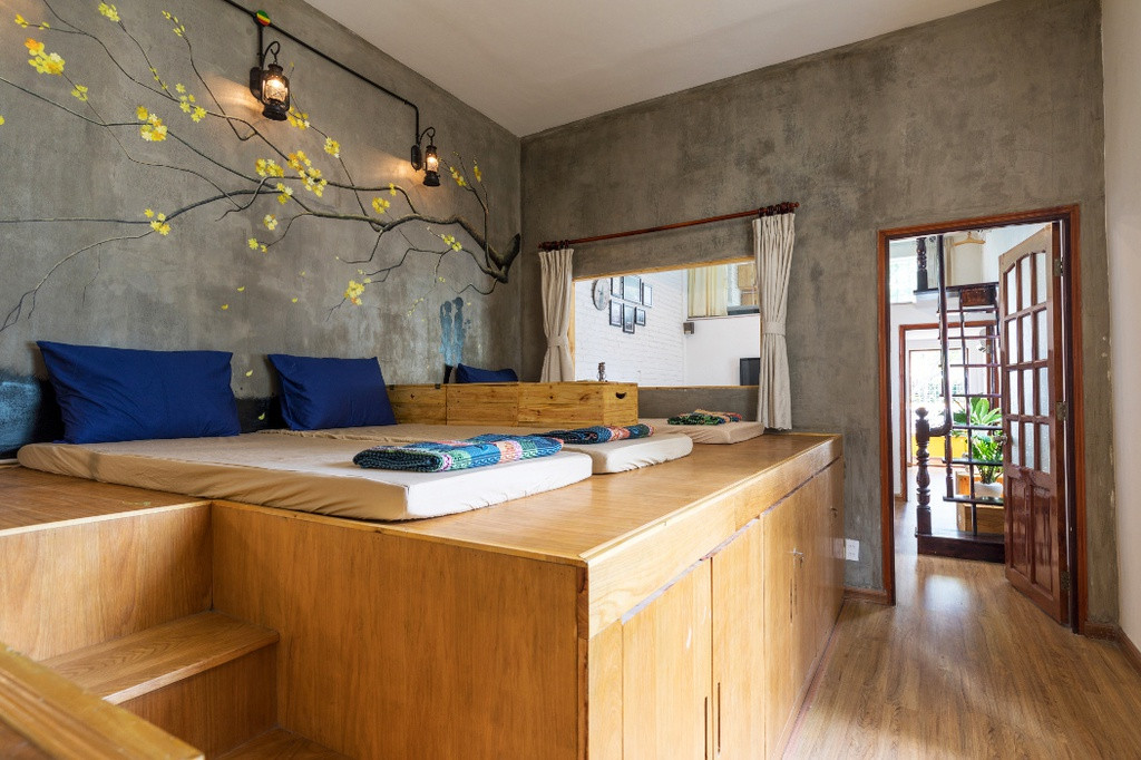 Phòng ngủ lớn được bố trí các tấm đệm thô kết hợp cùng màu xanh của chăn, gối. Phần tủ gỗ lớn có cầu thang vừa là nơi cất giữ đồ đạc vừa trở thành giường ngủ giúp tiết kiệm không gian và mang tới sự độc đáo cho căn phòng.