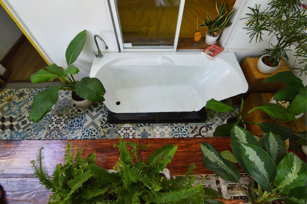 Một trong những nơi đặc biệt nhất của căn nhà chính là góc nhỏ ngoài ban công với chiếc ghế làm từ bồn tắm vây quanh bởi cây xanh mang đến không gian thư giãn, đọc sách trong lành giữa thành phố sôi động.