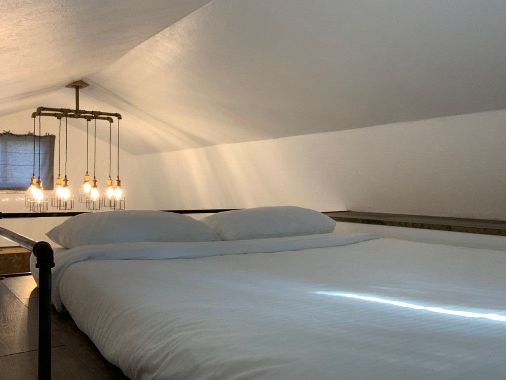 Phòng ngủ được bố trí đơn giản trên gác xép với một nệm lớn, một bục dài cạnh bên để sách và các vật dụng cá nhân. Cùng với đó là một cửa sổ nhỏ để nhìn ra sau nhà.