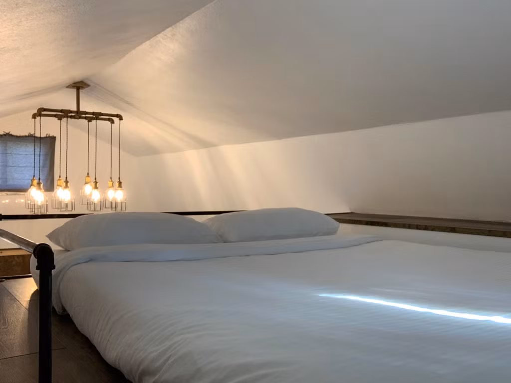 Phòng ngủ được bố trí đơn giản trên gác xép với một nệm lớn, một bục dài cạnh bên để sách và các vật dụng cá nhân. Cùng với đó là một cửa sổ nhỏ để nhìn ra sau nhà.