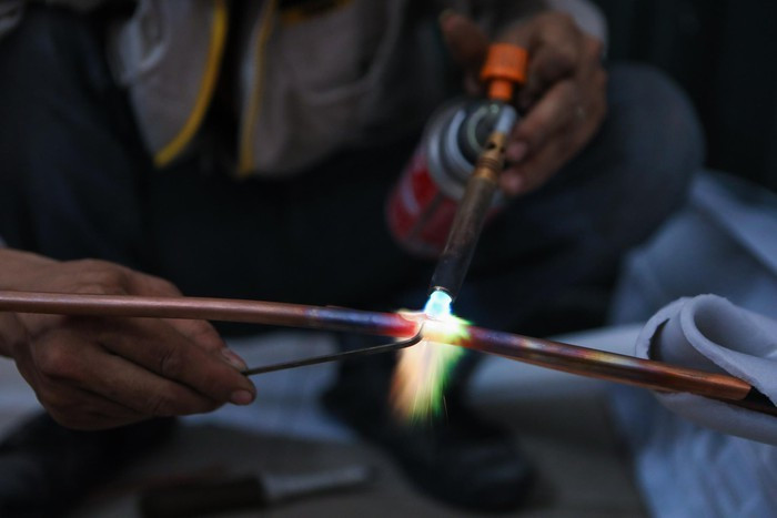 Tôi hàn ống đồng, luồn ống đồng vào dây giữ nhiệt cho cục lạnh. Đã quen công việc nên tôi làm nhanh và chính xác.