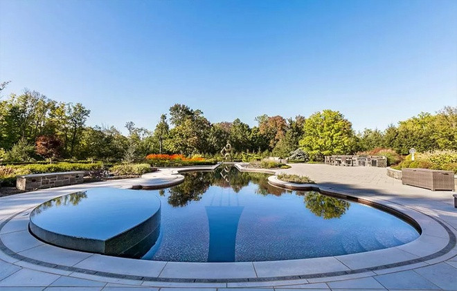 Hồ bơi cùng khu vực ăn uống ngoài trời được bao quanh bởi hàng cây cao lớn.