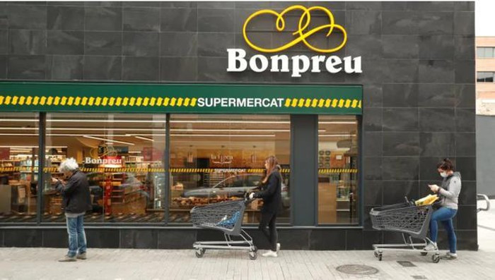 Khách hàng đứng cách xa nhau 2 m trước một cửa hàng ở Madrid, Tây Ban Nha. Ảnh: Reuters.