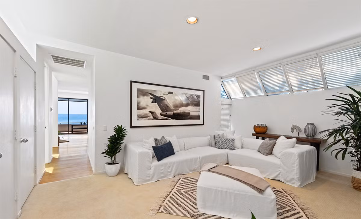 Phòng gia đình ấm áp, mang tông màu trắng chủ đạo, nổi bật với một chiếc thảm có hoạ tiết cầu kỳ.