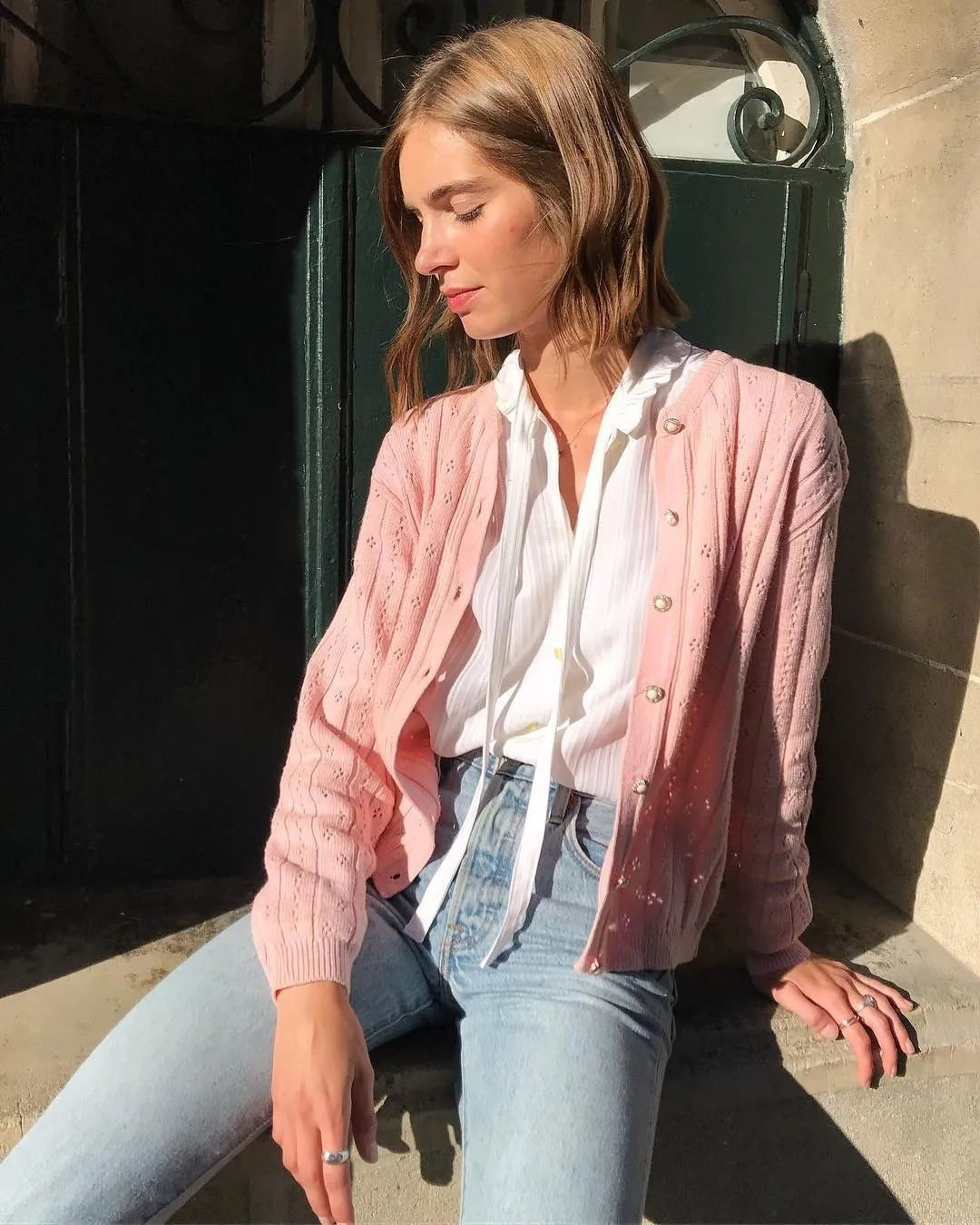 Chiếc cardigan màu hồng nhạt khoác ngoài áo sơ mi và quần jeans đã khiến set đồ công sở trông thú vị, mềm mại và nữ tính hơn rất nhiều.