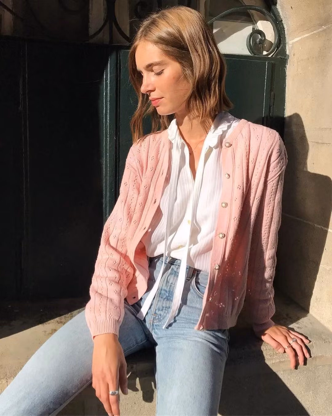 Chiếc cardigan màu hồng nhạt khoác ngoài áo sơ mi và quần jeans đã khiến set đồ công sở trông thú vị, mềm mại và nữ tính hơn rất nhiều.