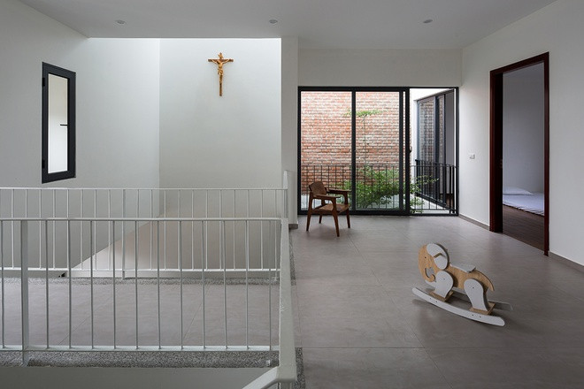 Tầng hai có hành lang nghỉ rất rộng để làm sân chơi cho trẻ nhỏ. Toàn bộ tường tầng một và tầng hai đều lấy chung một tông màu trắng với các khung cửa gỗ tối màu.