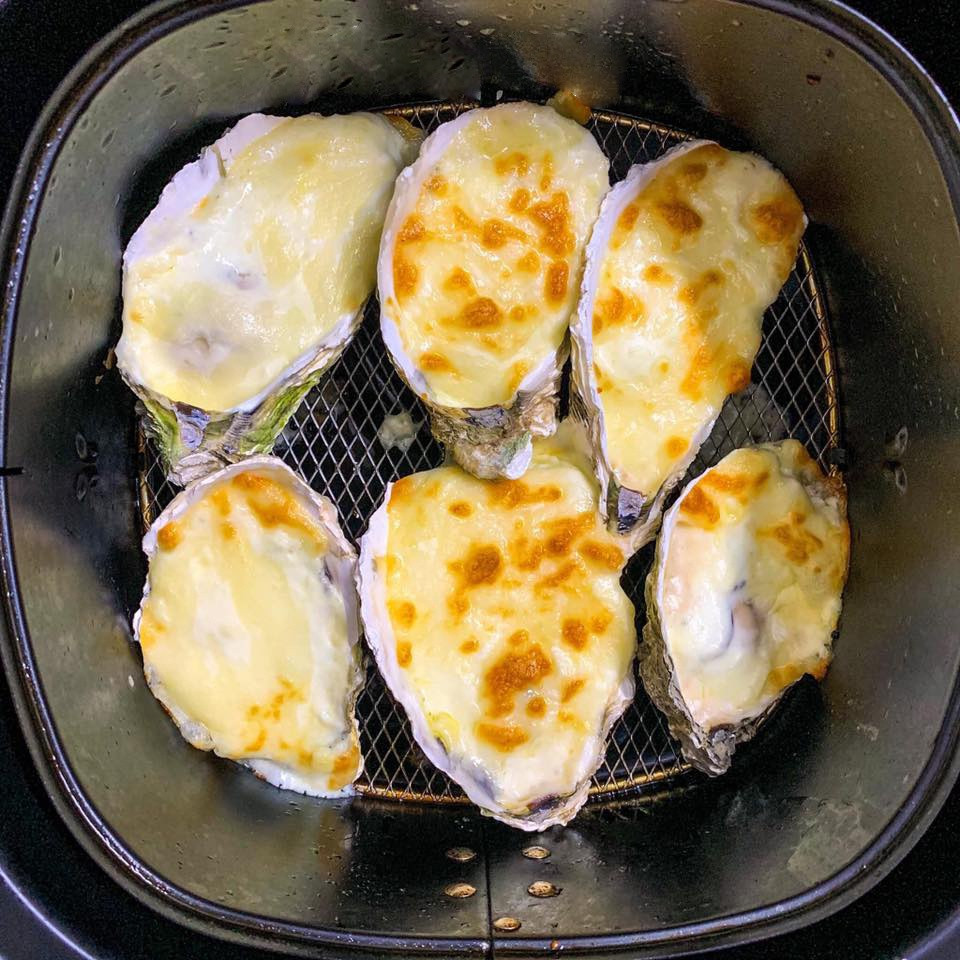  Hàu nướng phô mai: Để làm sốt phô mai, bạn trộn bột ngô, bột mì với sữa tươi không đường và whipping cream cho tan. Sau đó làm nóng chảo, cho bơ nhạt và tỏi băm nhuyễn, đảo cho tỏi hơi chín vàng thì đổ hỗn hợp ở trên vào, khuấy đều tay cho hỗn hợp hơi sánh mịn lại (có thể cho thêm chút bột canh). Xếp hàu vào vỉ nướng của nồi chiên không dầu, nướng trong 5 phút ở 160 độ C. Dùng kẹp gắp hàu ra đĩa, đổ phần nước hàu tiết ra đi. Phủ sốt phô mai vừa nấu xong lên từng con hàu, sau đó rắc phô mai sợi mozzarelle lên trên. Xếp lại hàu vào khay, nướng thêm 5 phút ở 180 độ C cho phô mai tan chảy và hơi xém.