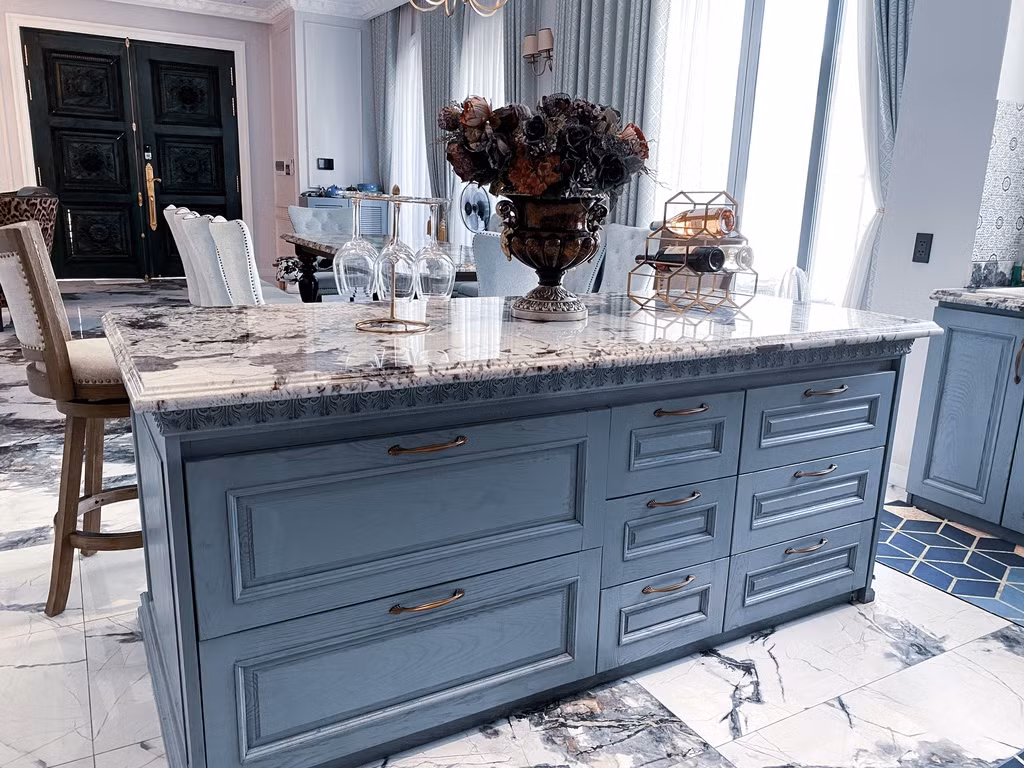 Đảo bếp có kích thước 1 m x 2 m được tận dụng làm ngăn đựng bát đĩa và đồ khô. Mặt trước của đảo bếp lùi vào 30 cm để có chỗ để chân khi ngồi lên ghế. Một mẹo nhỏ để giữ cho tủ bếp luôn sạch sẽ là việc sử dụng miếng lót ngăn tủ vừa giúp bảo vệ lớp gỗ bên dưới, vừa dễ vệ sinh.