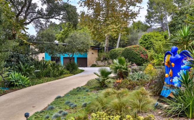 Ngôi nhà mang tông màu xanh ngọc đậm chủ đạo, tọa lạc ở một khu vực kín đáo, được bao quanh bởi hàng cây cao lớn để đảm bảo sự yên tĩnh và riêng tư cho gia chủ.